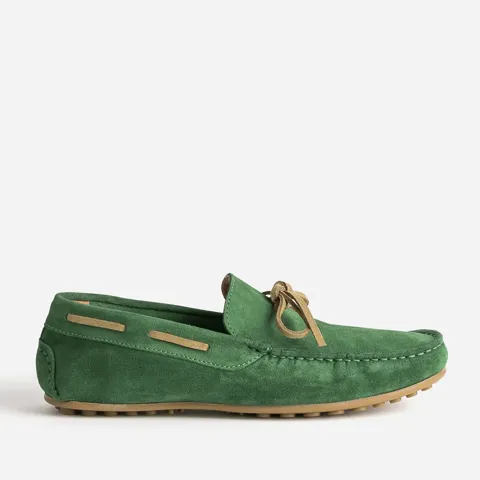 A pair of green suede driving loafers with a leather bow, on a white background